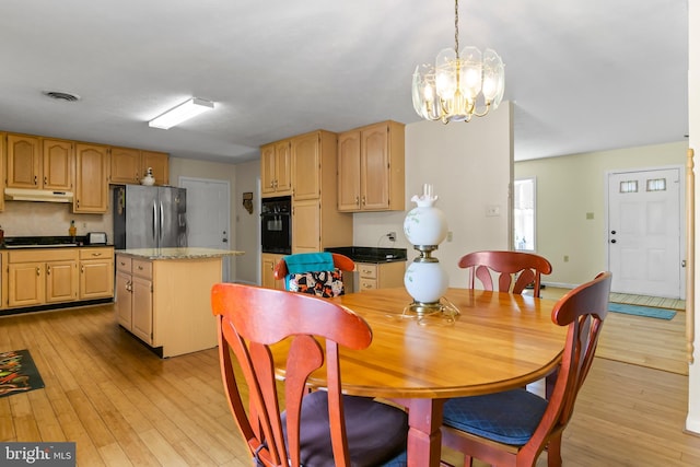 dining room with light wood-type flooring and a chandelier