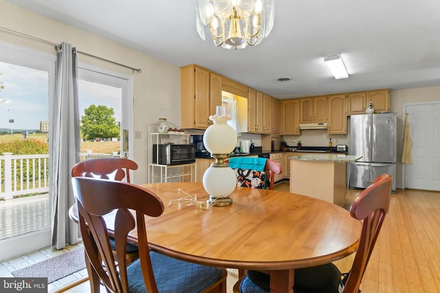 dining room with light wood-type flooring and an inviting chandelier