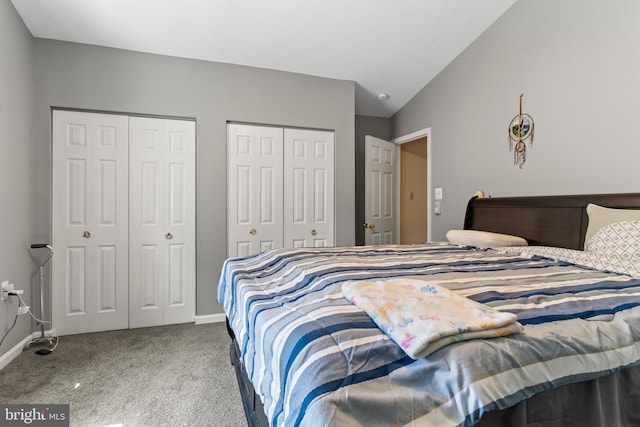 bedroom featuring carpet floors, vaulted ceiling, and two closets