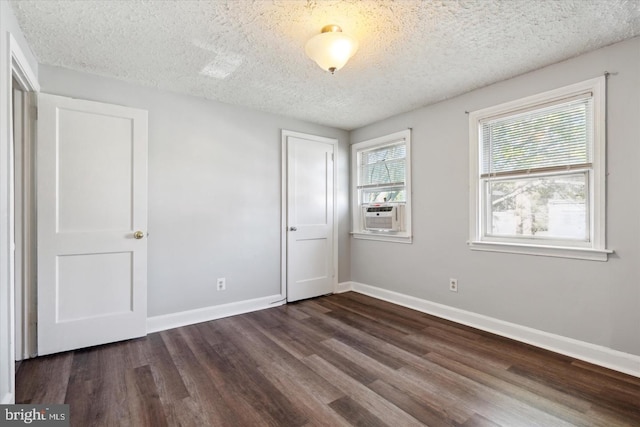 unfurnished bedroom with a textured ceiling, cooling unit, and dark wood-type flooring