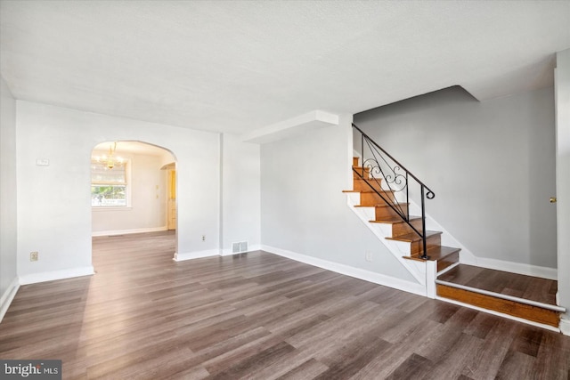 unfurnished room featuring wood-type flooring, a textured ceiling, and an inviting chandelier