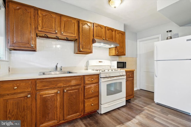 kitchen featuring tasteful backsplash, sink, wood-type flooring, and white appliances