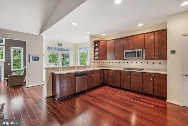 kitchen with decorative backsplash, appliances with stainless steel finishes, vaulted ceiling, dark wood-type flooring, and sink