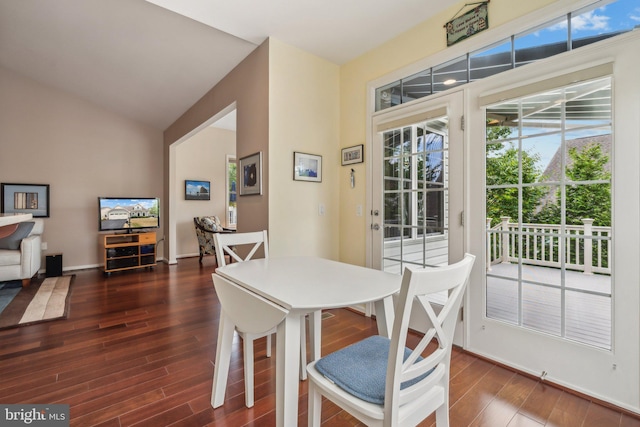 dining room featuring vaulted ceiling, a wealth of natural light, and dark wood-type flooring