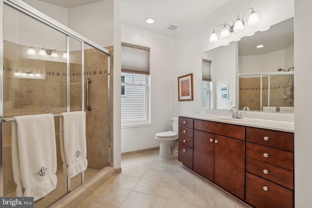 bathroom with tile patterned flooring, vanity, a shower with shower door, and toilet