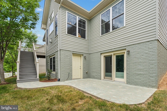 back of property featuring a patio area and a lawn