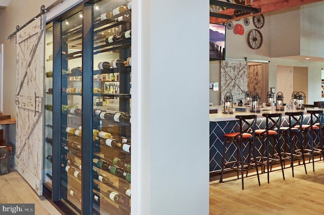 wine room featuring a barn door, hardwood / wood-style flooring, and bar