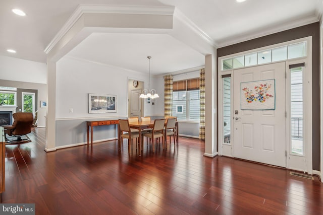 foyer entrance featuring ornamental molding, a wealth of natural light, and an inviting chandelier