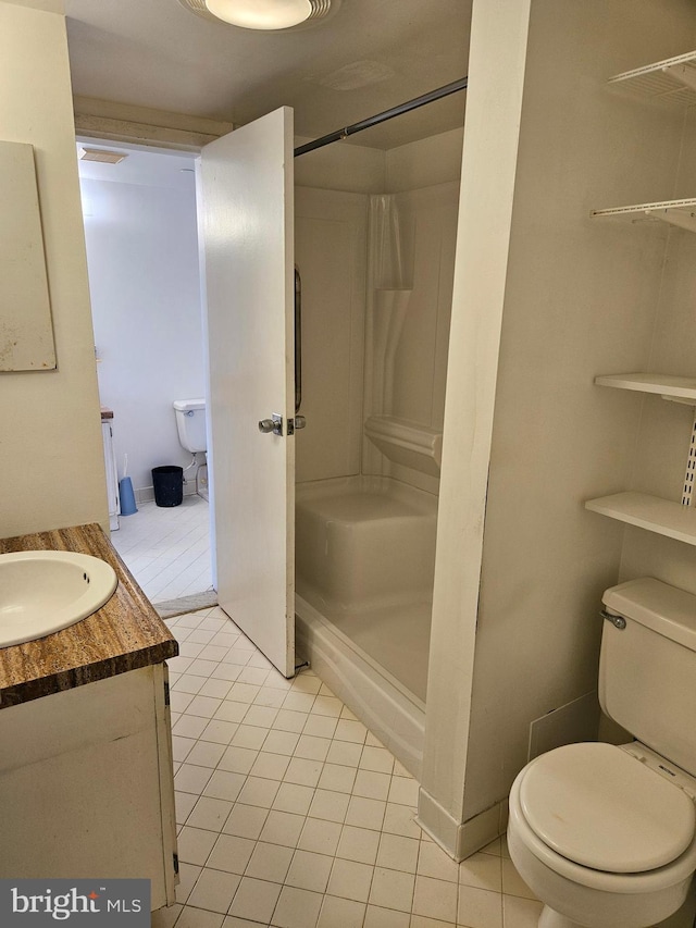 bathroom with walk in shower, vanity, toilet, and tile patterned flooring