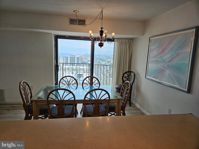 dining room with a wealth of natural light, hardwood / wood-style floors, a textured ceiling, and a notable chandelier