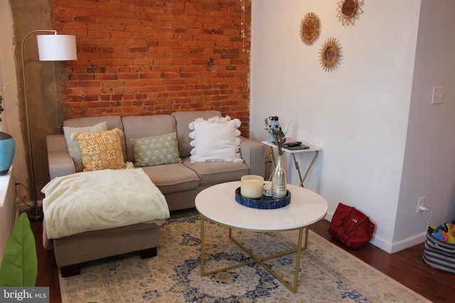 living room with dark hardwood / wood-style floors and brick wall