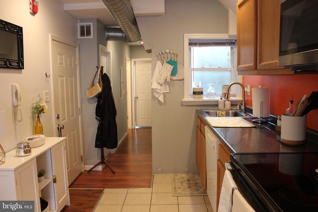 kitchen featuring dishwasher, electric range, light hardwood / wood-style flooring, and sink