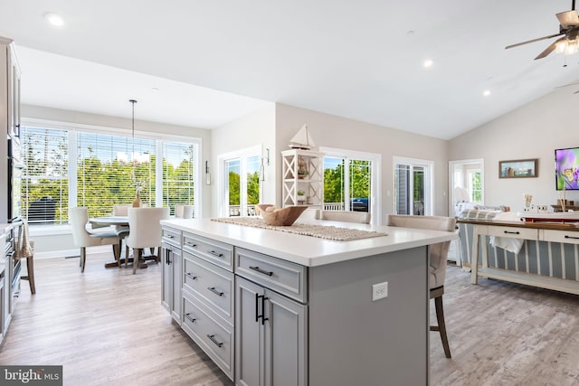 kitchen featuring gray cabinetry, vaulted ceiling, pendant lighting, light hardwood / wood-style flooring, and a center island