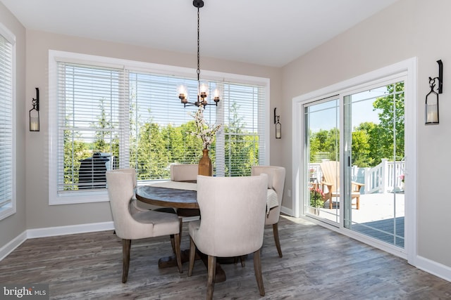 dining area with plenty of natural light, dark hardwood / wood-style flooring, and an inviting chandelier