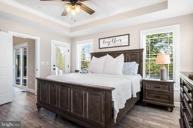 bedroom with access to exterior, ceiling fan, crown molding, a tray ceiling, and hardwood / wood-style flooring