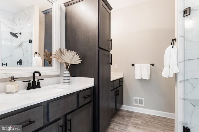 bathroom with hardwood / wood-style floors, vanity, and a shower with shower door