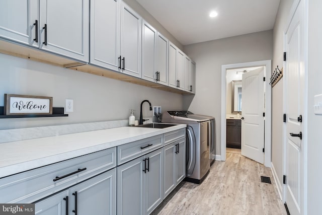 washroom featuring cabinets, hookup for a washing machine, light hardwood / wood-style floors, and sink