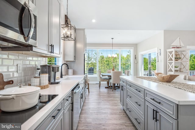 kitchen featuring tasteful backsplash, gray cabinetry, pendant lighting, and stainless steel appliances