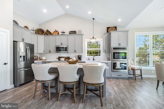 kitchen featuring gray cabinets, a center island, stainless steel appliances, and decorative light fixtures