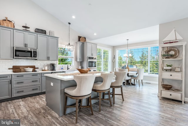 kitchen with appliances with stainless steel finishes, decorative light fixtures, a kitchen island, and gray cabinetry