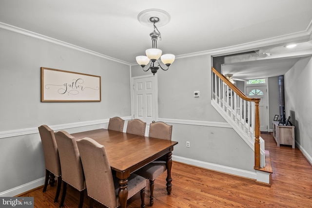 dining space featuring hardwood / wood-style floors, crown molding, and a chandelier