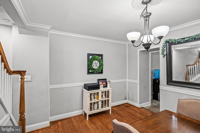 dining room featuring wood-type flooring, crown molding, and a notable chandelier