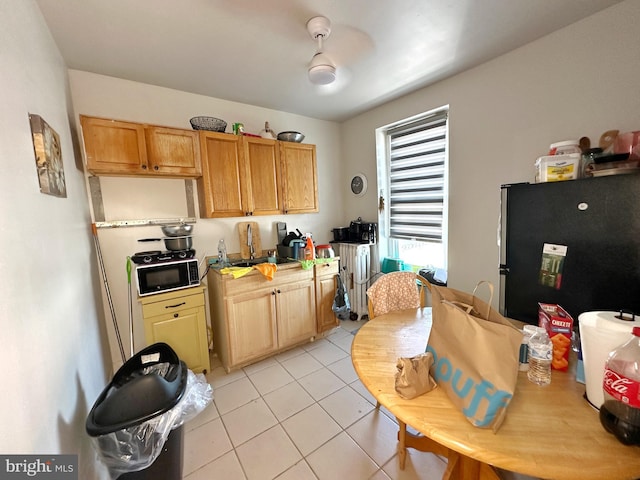 kitchen featuring stainless steel fridge, sink, light tile patterned flooring, and ceiling fan