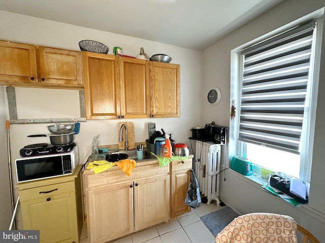 kitchen with light tile patterned flooring, radiator heating unit, and sink