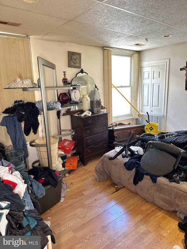 bedroom with a closet, light hardwood / wood-style flooring, and a drop ceiling