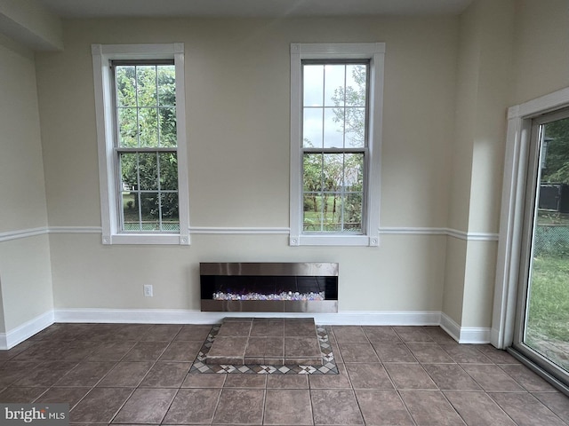 unfurnished living room with dark tile patterned floors and a wealth of natural light