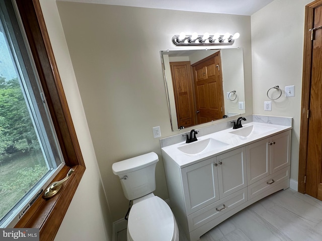 bathroom featuring toilet and double sink vanity