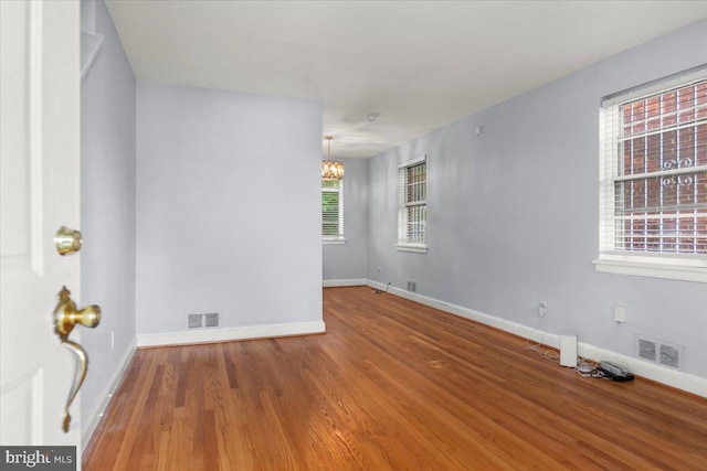 unfurnished room with wood-type flooring and a chandelier