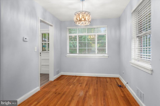 unfurnished dining area with hardwood / wood-style flooring and a notable chandelier