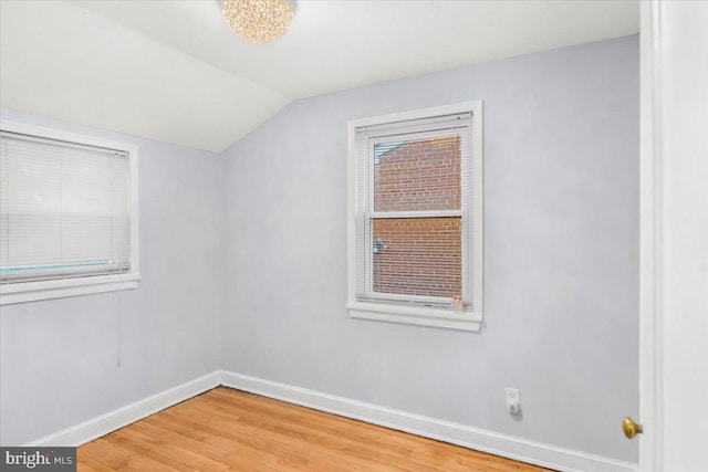 additional living space with hardwood / wood-style flooring and vaulted ceiling