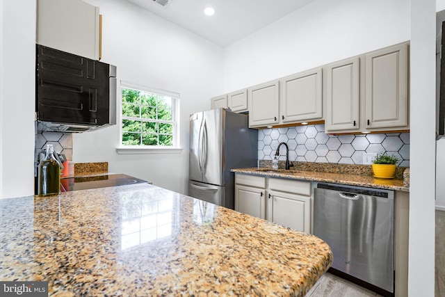 kitchen with backsplash, light stone counters, sink, and stainless steel appliances