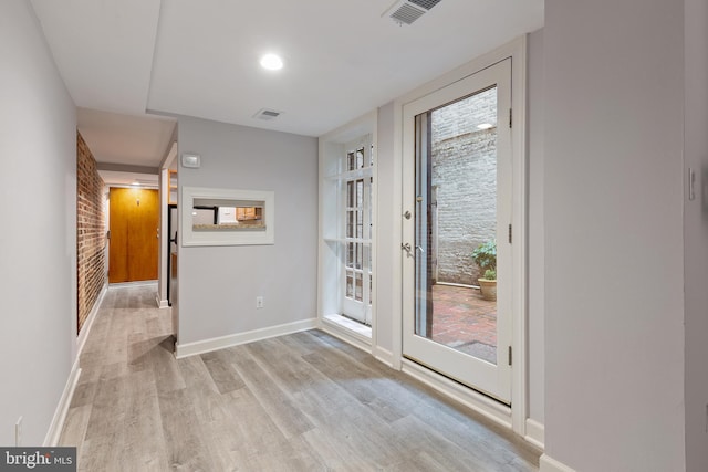 entryway with plenty of natural light, brick wall, and light hardwood / wood-style flooring