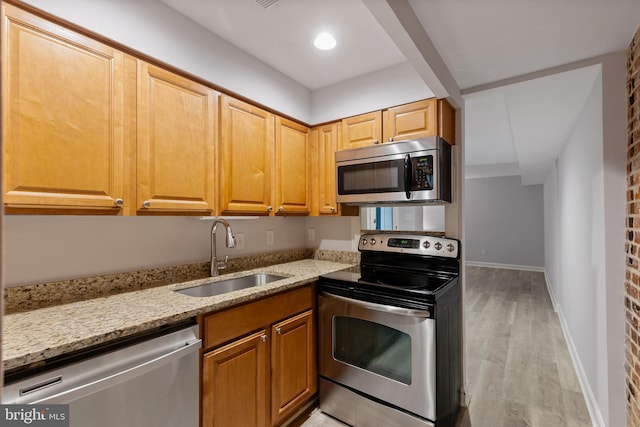 kitchen with sink, light stone countertops, stainless steel appliances, and light wood-type flooring