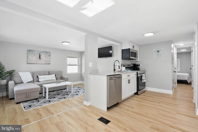 kitchen with white cabinets, appliances with stainless steel finishes, light hardwood / wood-style floors, and sink