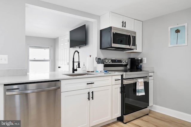 kitchen with white cabinetry, sink, stainless steel appliances, and light wood-type flooring