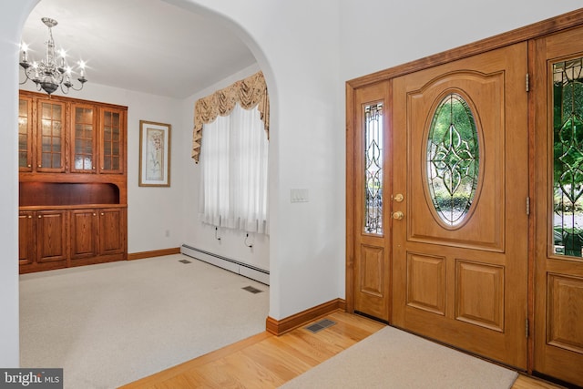 foyer with baseboard heating, a chandelier, and light wood-type flooring