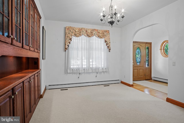 carpeted entrance foyer with baseboard heating and a chandelier