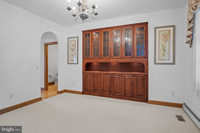 spare room featuring light carpet, baseboard heating, and a notable chandelier