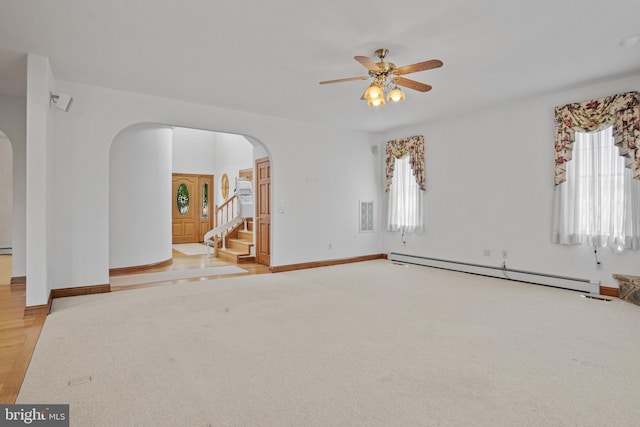 empty room featuring a wealth of natural light, baseboard heating, and ceiling fan