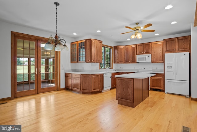 kitchen featuring ceiling fan with notable chandelier, white appliances, light hardwood / wood-style flooring, and hanging light fixtures