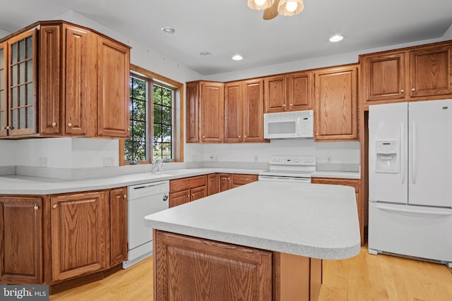 kitchen with sink, a kitchen island, light hardwood / wood-style floors, and white appliances