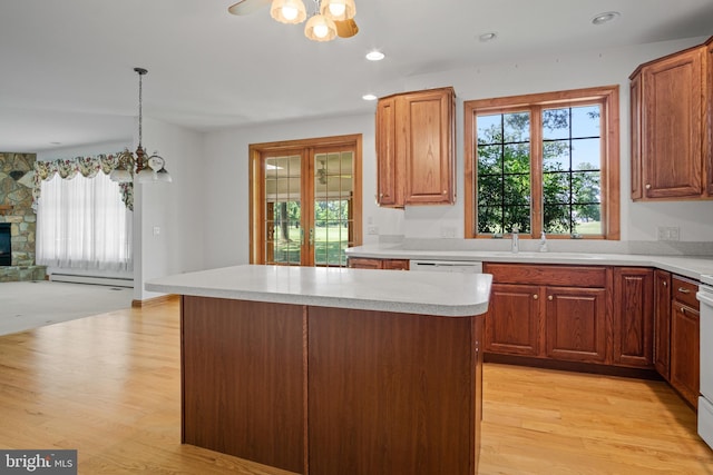 kitchen featuring sink, a baseboard radiator, pendant lighting, light hardwood / wood-style floors, and a fireplace