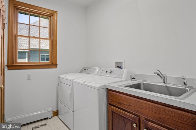 clothes washing area featuring cabinets, a baseboard heating unit, sink, light tile patterned floors, and washing machine and clothes dryer