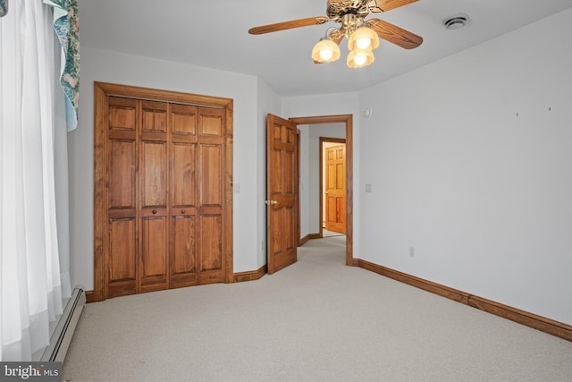 unfurnished bedroom with ceiling fan, a closet, light colored carpet, and a baseboard heating unit