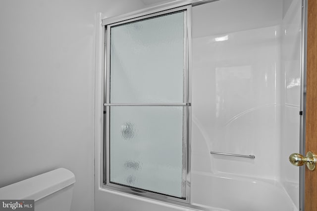 bathroom featuring toilet and bath / shower combo with glass door