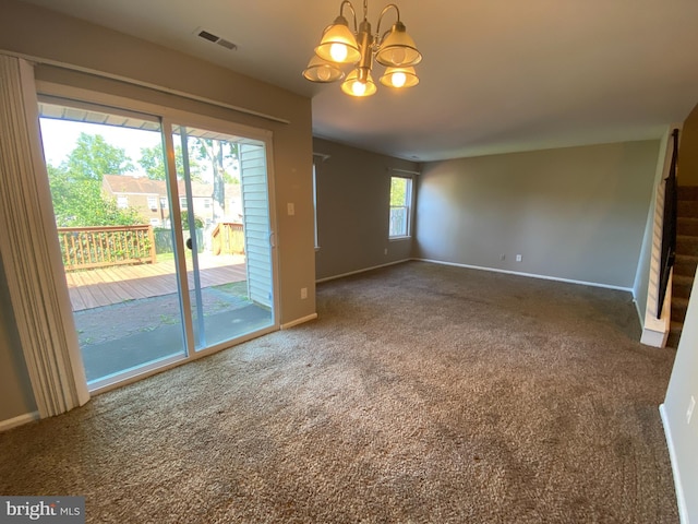 empty room with carpet flooring, plenty of natural light, and a chandelier